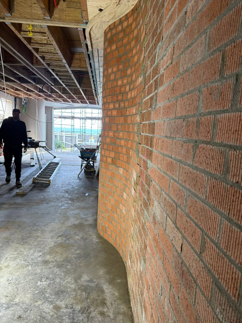 Curved face-brick feature wall inside a building under construction